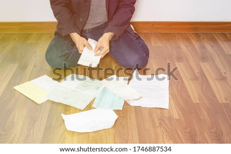 Light filter effect on man checking and reading bills and paper on the floor