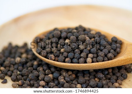 Close up black peper in wooden spoon pile and heap of black peper in Wooden plate on white background.Thai Indian Spice. Royalty-Free Stock Photo #1746894425