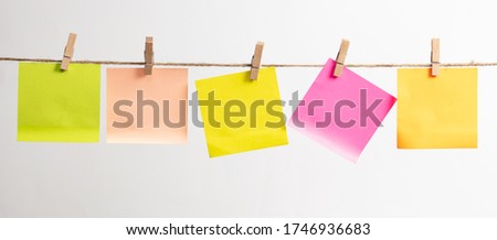 Colored papers hang on a rope on a white background.
