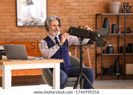 Senior photographer with lighting equipment in studio