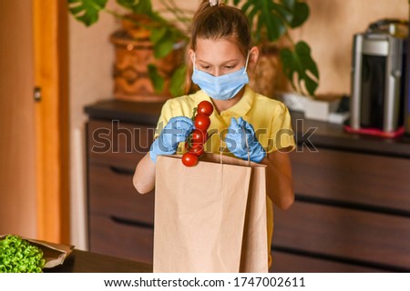 little girl with laptop. young woman holding blank sign. Coronavirus. Woman with face mask on quarantine, cooks in the kitchen at home during coronavirus crisis. Stay at home. Enjoy cooking at home. 