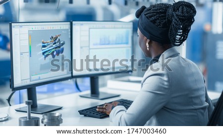 Beautiful Female Engineer Working on Personal Computer in the High-Tech Industrial Factory, She Uses CAD Software Designing 3D Turbine. Over the Shoulder Shot.