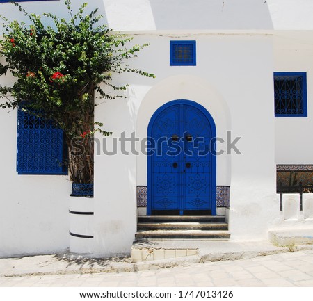 Traditional blue Tunisian metal door with a black pattern in a white building in the city of Sidi Bou Said in Tunisia in the summer on a sunny day Royalty-Free Stock Photo #1747013426