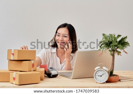 Young attractive asian woman online seller working on laptop computer checking order on internet at home preparing for delivery at from home