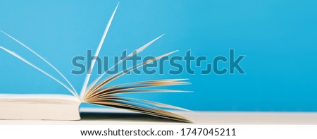close-up panoramic picture of open book on blue background. reading, education, literature, learning and back to school concept.  copy space. 