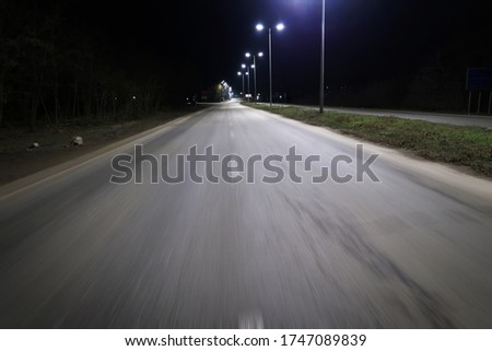 Dark night empty asphalt road in motion and lampposts