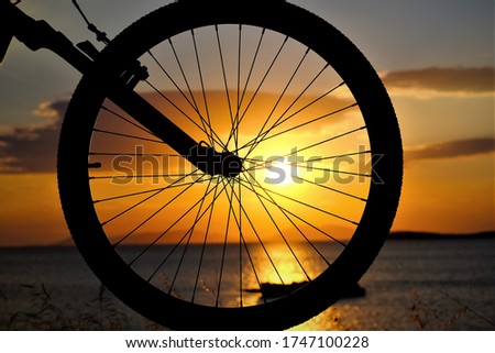 Amazing silhoutte of a bicycles whell at the sunset in a colorful cloudy sky