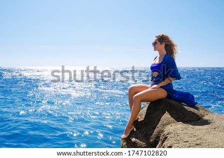Attractive young woman in blue swimsuit on sea coast