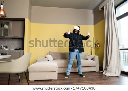 Man showing like gesture while using virtual reality headset in living room