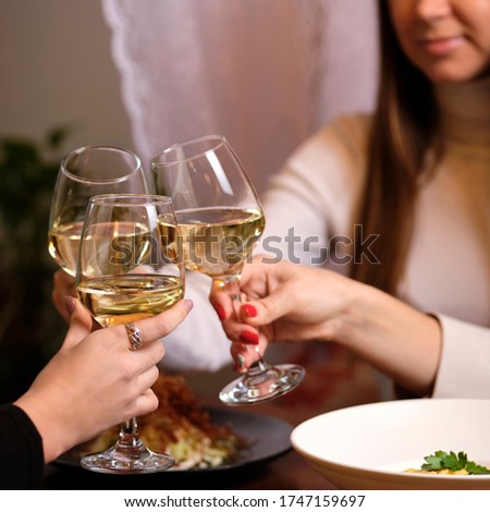female friends - hands clinking white wine glasses, restaurant or bar on background, close up view. evening, celebration and holidays concept
