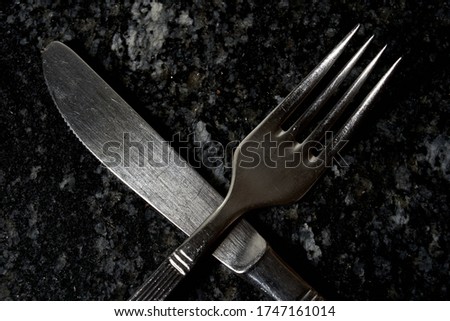 fork and crossed knife on black background
