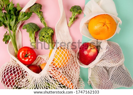 Top view of mesh shopping bag with organic eco vegetables on color background. Caring for the environment and the rejection of plastic concept