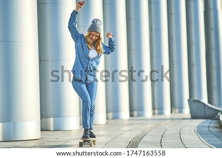 Stylish woman riding on skateboard outdoor. Big city lifestyle concept.