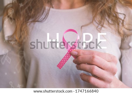 Girl  hands holding pink ribbon, breast cancer awareness month, concept of health. 