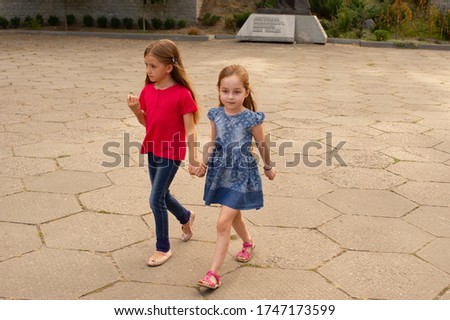 Sisters, Outdoor photo from two little girls. Two little girls walk in the park by the hand. Sisters for a walk in the summer or autumn on the street. Girlfriends, children, nature. Family concept.