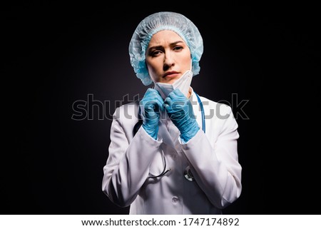 Photo of tired exhausted lady doc hold arms taking off protective mask after last late operation breathe in fresh air wear gloves lab white coat surgical cap isolated black color background
