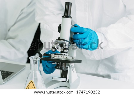 The Microscope of Lab Technician in Personal protective equipment  PPE suit Vaccines testing of Virus