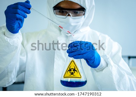 Lab Technician in Personal protective equipment  PPE suit Vaccines testing of Virus holding the hazardous lab glass bottle
