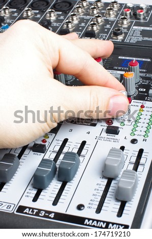Male hand adjusting audio mixer desk
