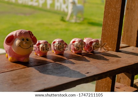 A picture of plaster of 5 sheep, all at a wooden table