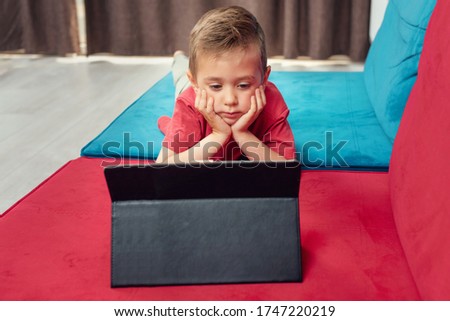 Portrait of a young kid at home watching cartoon on the tablet
