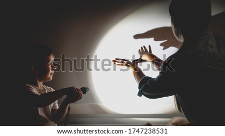 Toned photo of young mother and little boy playing in theater of shadows before going to sleep at night. Royalty-Free Stock Photo #1747238531