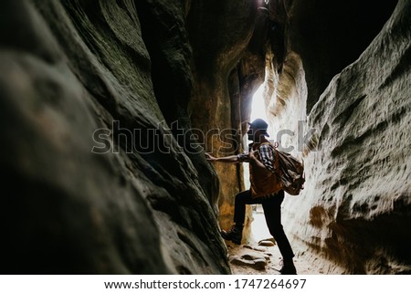 The traveler stands in a mountain cave. Hiking in the mountains