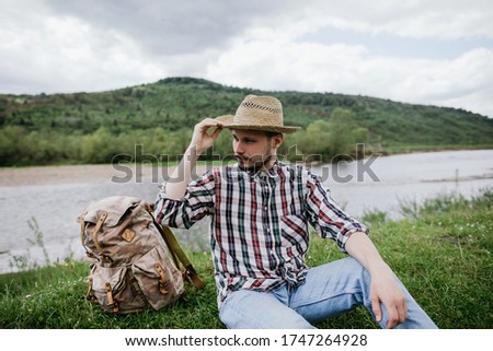 Portrait of a handsome young bearded hipster man in a straw hat outdoors
