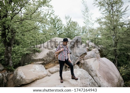 Young male hiker standing on top of a cliff with a backpack