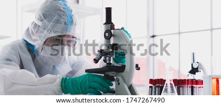 banner picture of scientist in personal protective equipment or ppe doing research and experiment to find vaccine to treat covid-19 or coronavirus infection in the lab