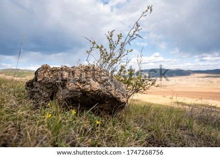 stone lying near the field against the sky and rural landscape, horizontally
