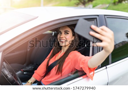 Smiling young woman taking selfie picture with smart phone camera outdoors in car. Holidays and tourism concept - smiling teenage girl taking selfie picture with smartphone camera outdoors in car