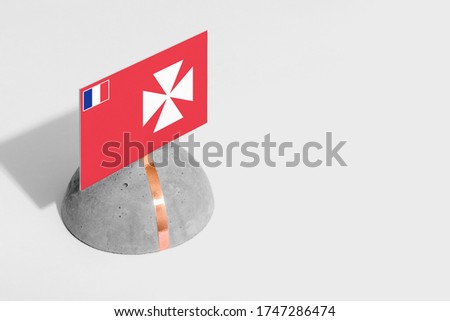Wallis And Futuna flag tagged on rounded stone. White isolated background. Side view minimal national concept.