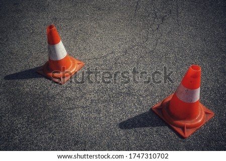Two bicolor road cones on the asphalt