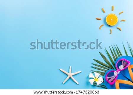 Summer holiday and vacation concept. Beach accessories sunglasses, starfish, sun, flower and palm leaf on blue pastel background with copy space for text.Top view.Summer time.