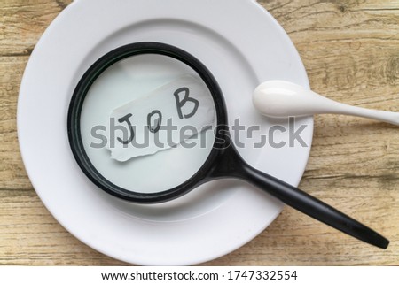 magifier and 'job' handwriting on paper with spoon and plate, find a job for living concept.
