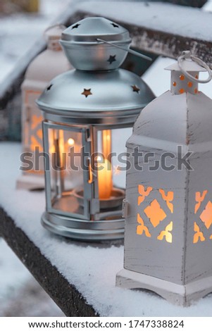 Lamp on a snowy staircase in winter. Сandles and candlesticks on a winter staircase in the snow. Picture for Christmas background. Warm winter photography