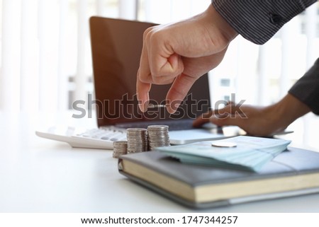 Businessmen count incremental coins from the company's profitability instead of using graph paper to help reduce waste. Royalty-Free Stock Photo #1747344257