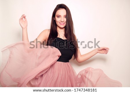 Beauty brunette girl with long hair. Model in a pink dress, flying dress, fabric. Pink makeup, style, fashion, beauty photo.