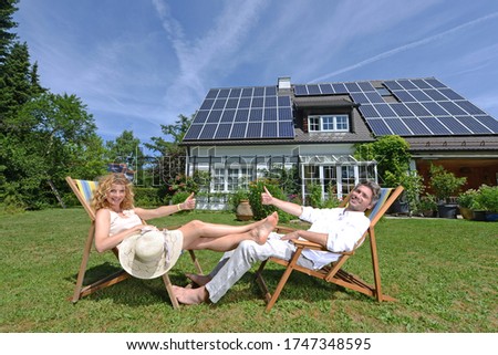 Mid adult couple in deckchairs in garden of solar paneled house Royalty-Free Stock Photo #1747348595