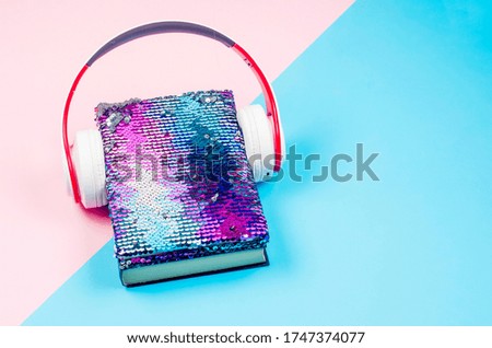phone with earphones and book on colored paper background. Audio book concept. modern education, reading. Listening to audiobooks, podcasts, and online courses. 