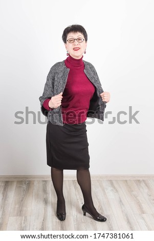 Senior buisness woman standing isolated on grey studio background. She looking at camera at office