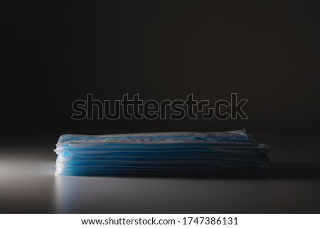 A stack of surgical mask with spotlight effect from left in isolated black background. New mask.
