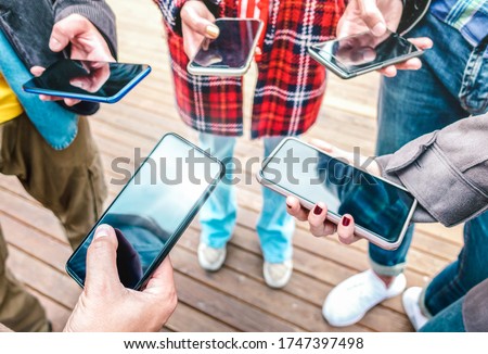 Close up of hands using mobile smart phones - People detail sharing photos on social media network with tech device - Technology concept and cellphone usage with selective focus on left smartphone