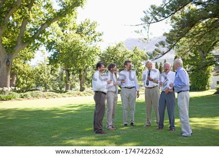 A group of men drinking champagne at an outdoor wedding reception