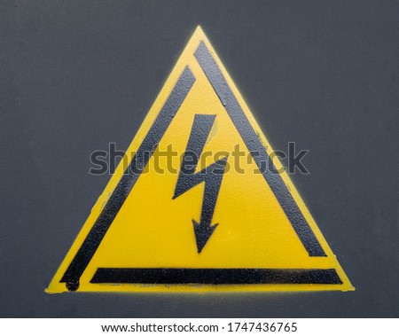 Warning sign against electric shock. The frame is black in the form of a triangle. Inside the yellow triangle is a Black lightning bolt. Black background. Caution, high voltage.