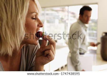 Man watching girlfriend eat strawberry
