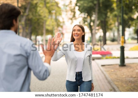 Just Friends. Girl Waving Hello Meeting Guy Walking In Park Outside. Selective Focus Royalty-Free Stock Photo #1747481174