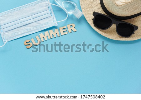 Summer layout with straw hat, sunglasses, summer wooden letters sanitizer medical mask. Concept of travel and recreation. Flights to sea, rest during coronavirus. Vacation Flatly on blue Royalty-Free Stock Photo #1747508402