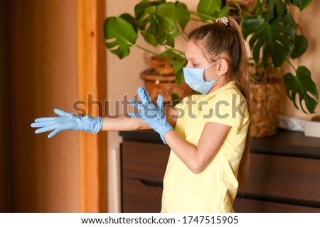  young woman holding blank sign. Coronavirus. Woman with face mask on quarantine, cooks in the kitchen at home during coronavirus crisis. Stay at home. Enjoy cooking at home. Family concept.